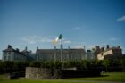 The irish flag flies in front of a large building.